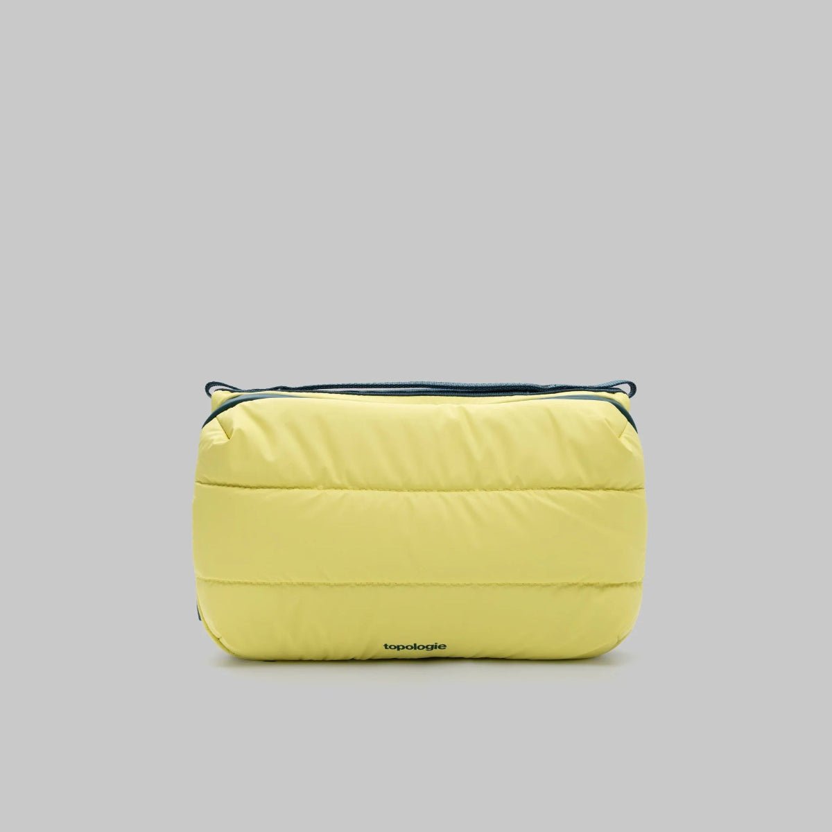 Canary yellow large puffy bottle bag from topologie with green zipper on a gray background