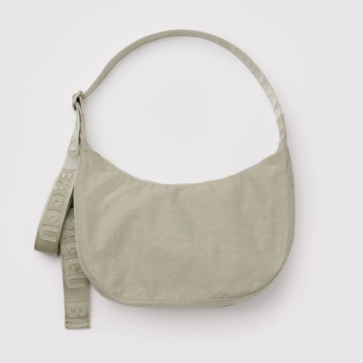 Baggu crescent shoulder bag in neutral fabric with adjustable strap, showcasing its stylish, compact design.