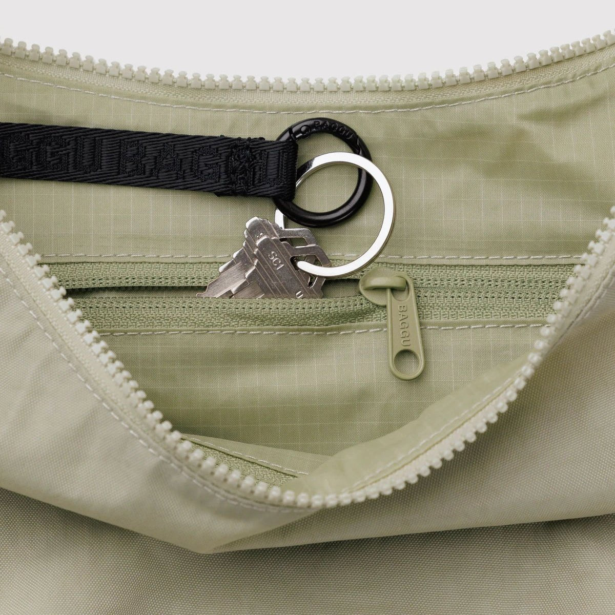 Baggu Crescent Shoulder Bag in neutral fabric with adjustable strap, featuring a sleek, rounded design and spacious interior.