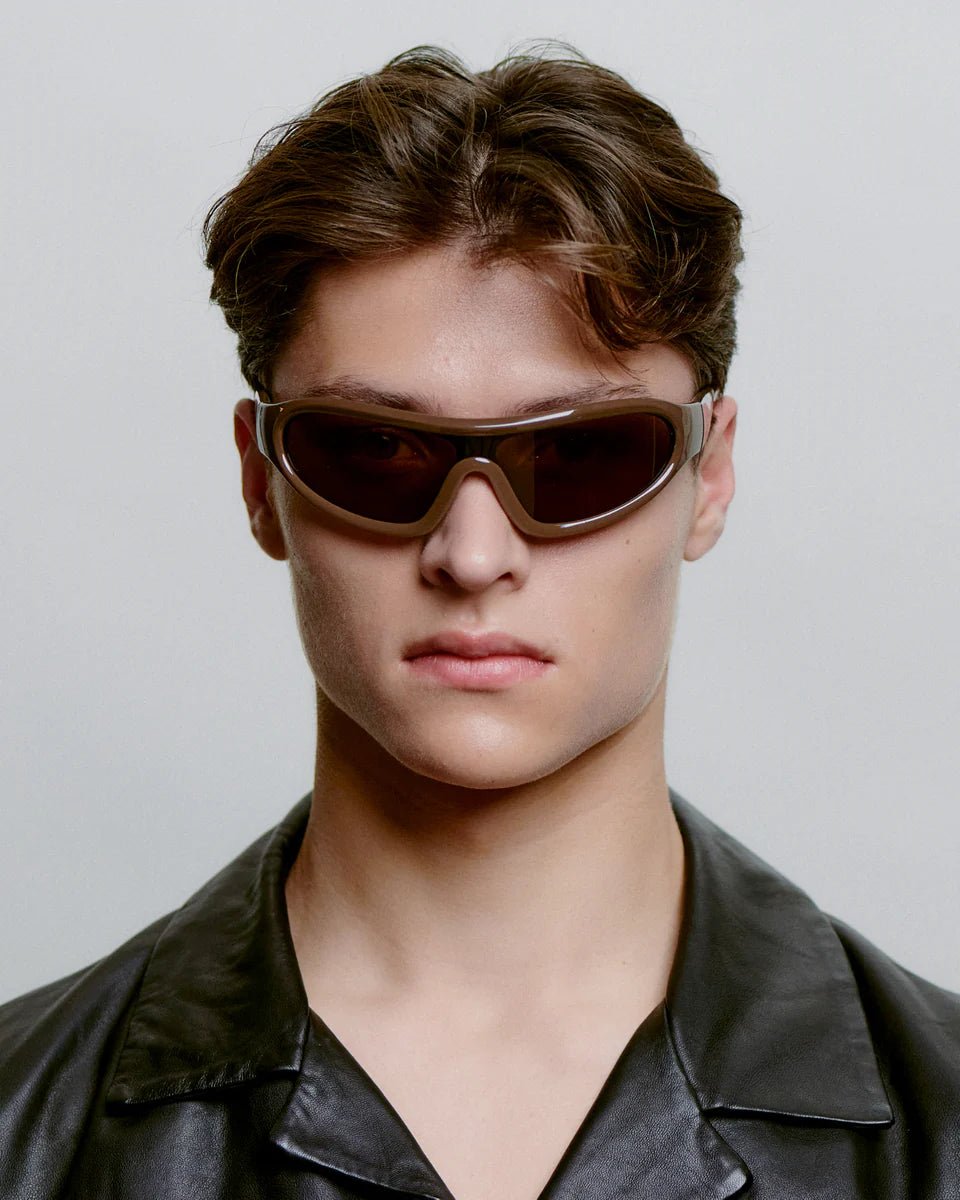 Chocolate brown A. Kjaerbede Devon sunglasses with rounded frames and tinted lenses, stylishly displayed on a neutral background.