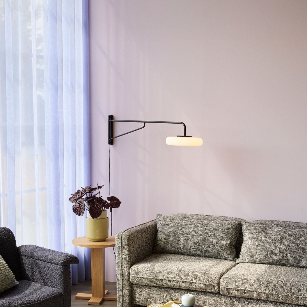 Black Hübsch Sway Wall Lamp mounted on a wall, showcasing its modern, minimalist lighting design with a sleek, curved form.