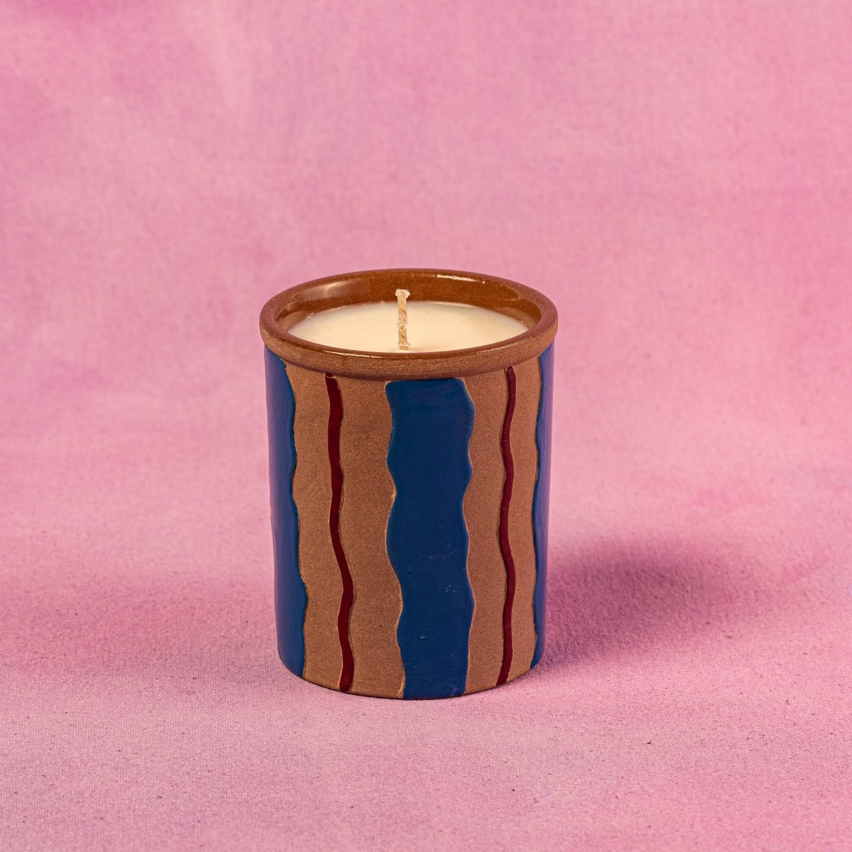 Ceramic candle with wavy design on a pink background