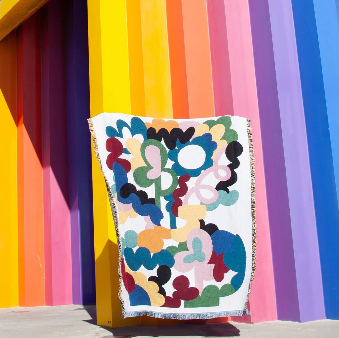 Colorful floral-patterned blanket against a multicolored striped background