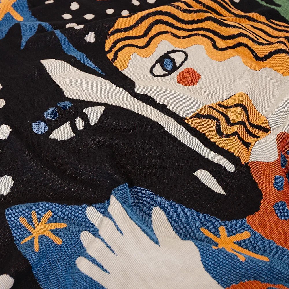 Close-up of a colorful embroidered design featuring a face with orange hair, black suit, and white gloves.