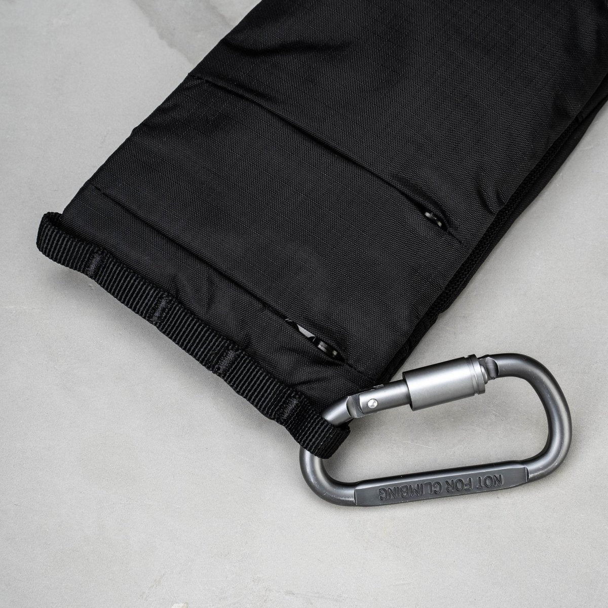 Black bag with a silver carabiner on a light gray background