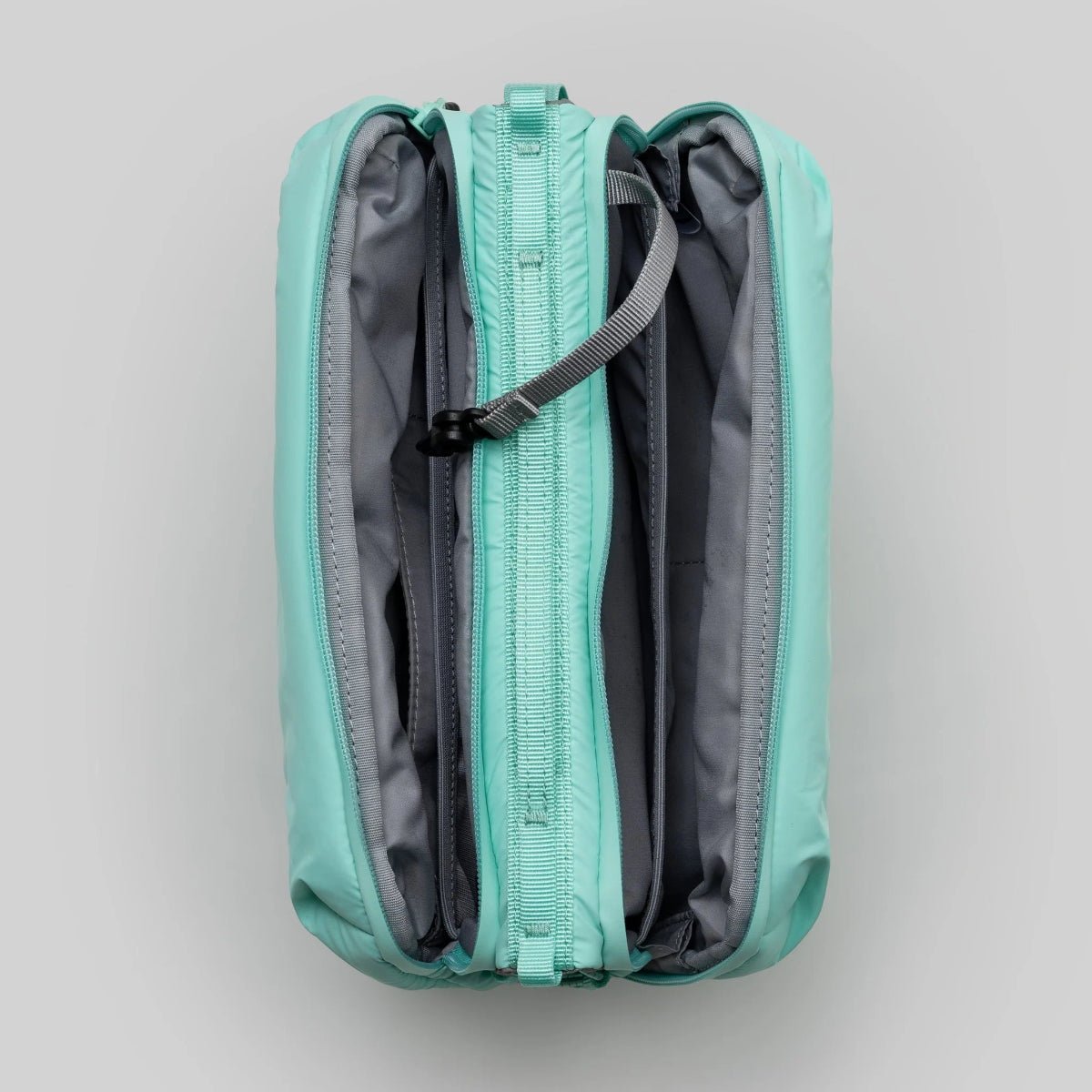 Large puffy mint green bottle bag from topologie shot from above with the zips open on a gray background