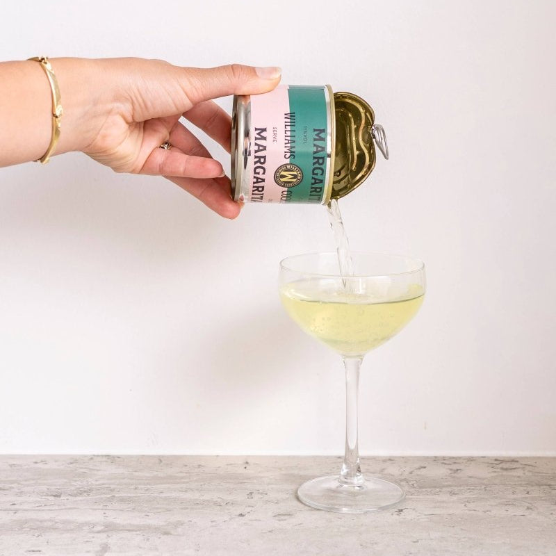 Williams Premium Canned Cocktails Margarita features a clear glass with a vibrant, tangy lime margarita garnished with a lime wedge.