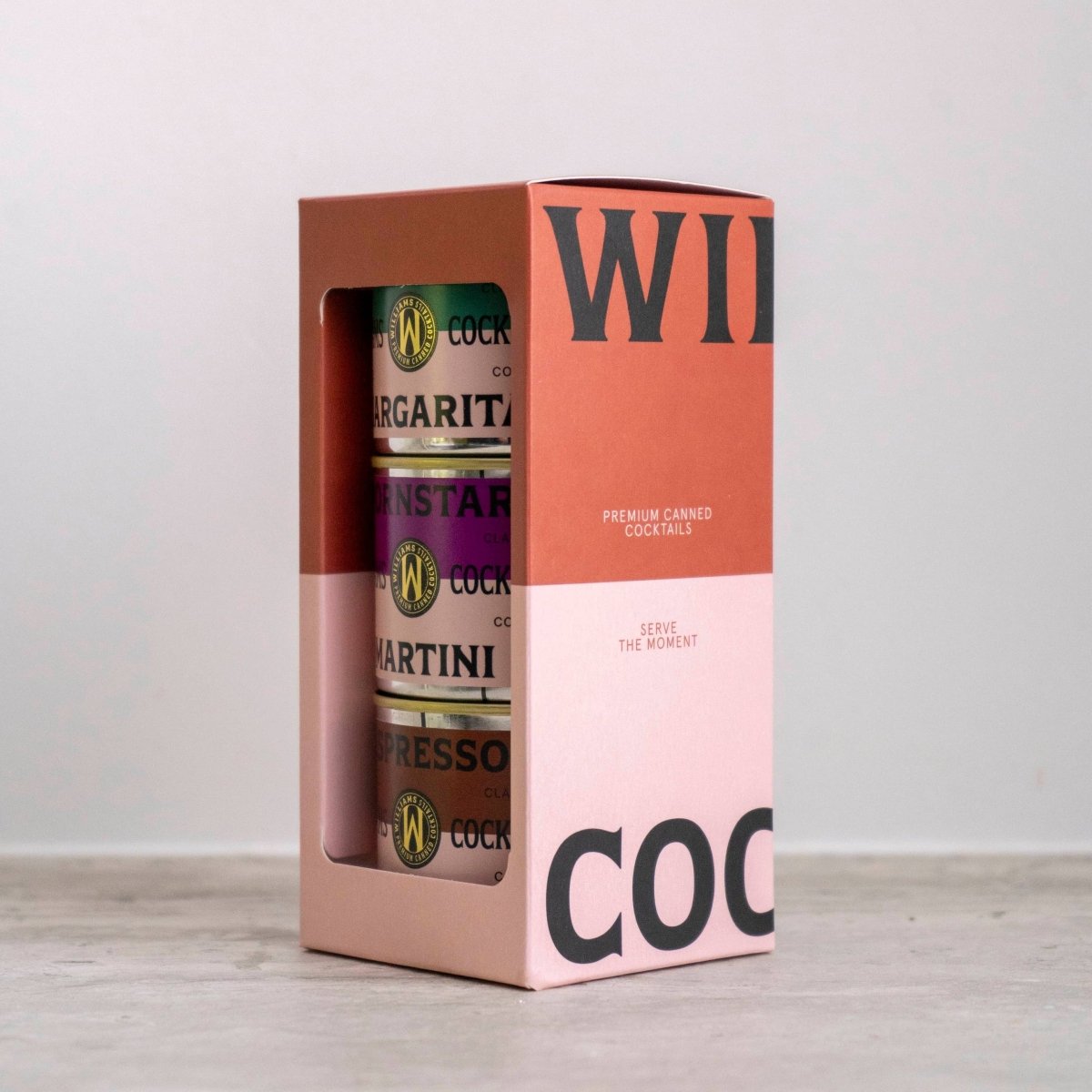 Set of three Williams Premium Canned Cocktails featuring colorful cans with fruit illustrations and cocktail images.