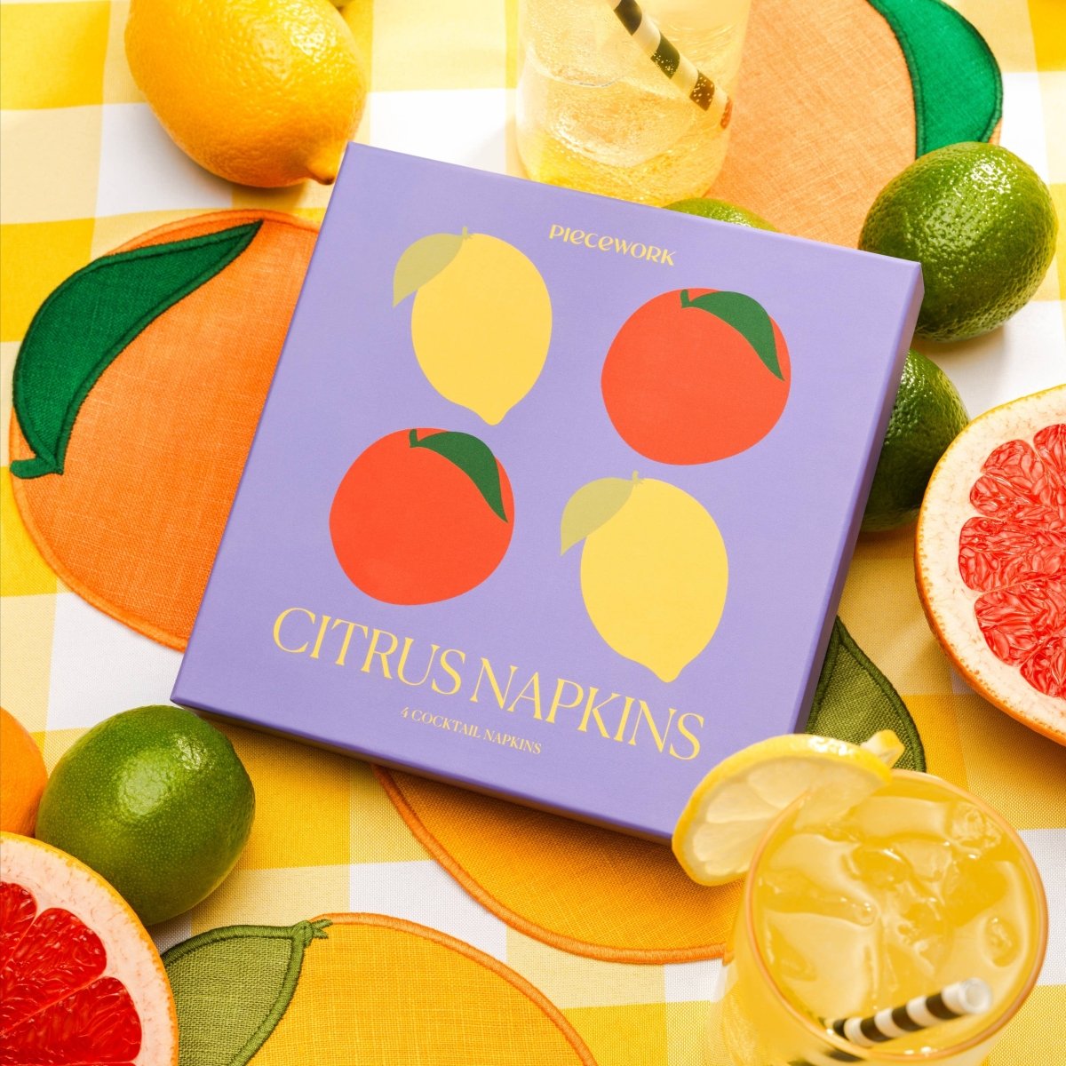 Citrus-themed napkins with lemons, oranges, and limes on a checkered tablecloth.