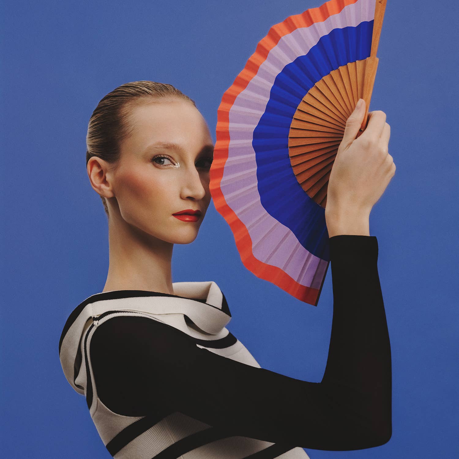 A FAN OF Fluid Shapes MIDI fan in 23 cm with blue, lilac, and orange colors, featuring a modern wave design.