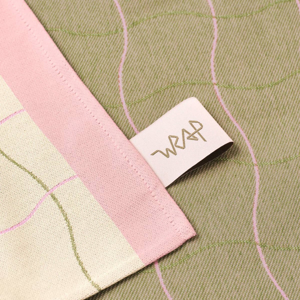 Close-up of a fabric with pink and green patterns and a visible brand tag.