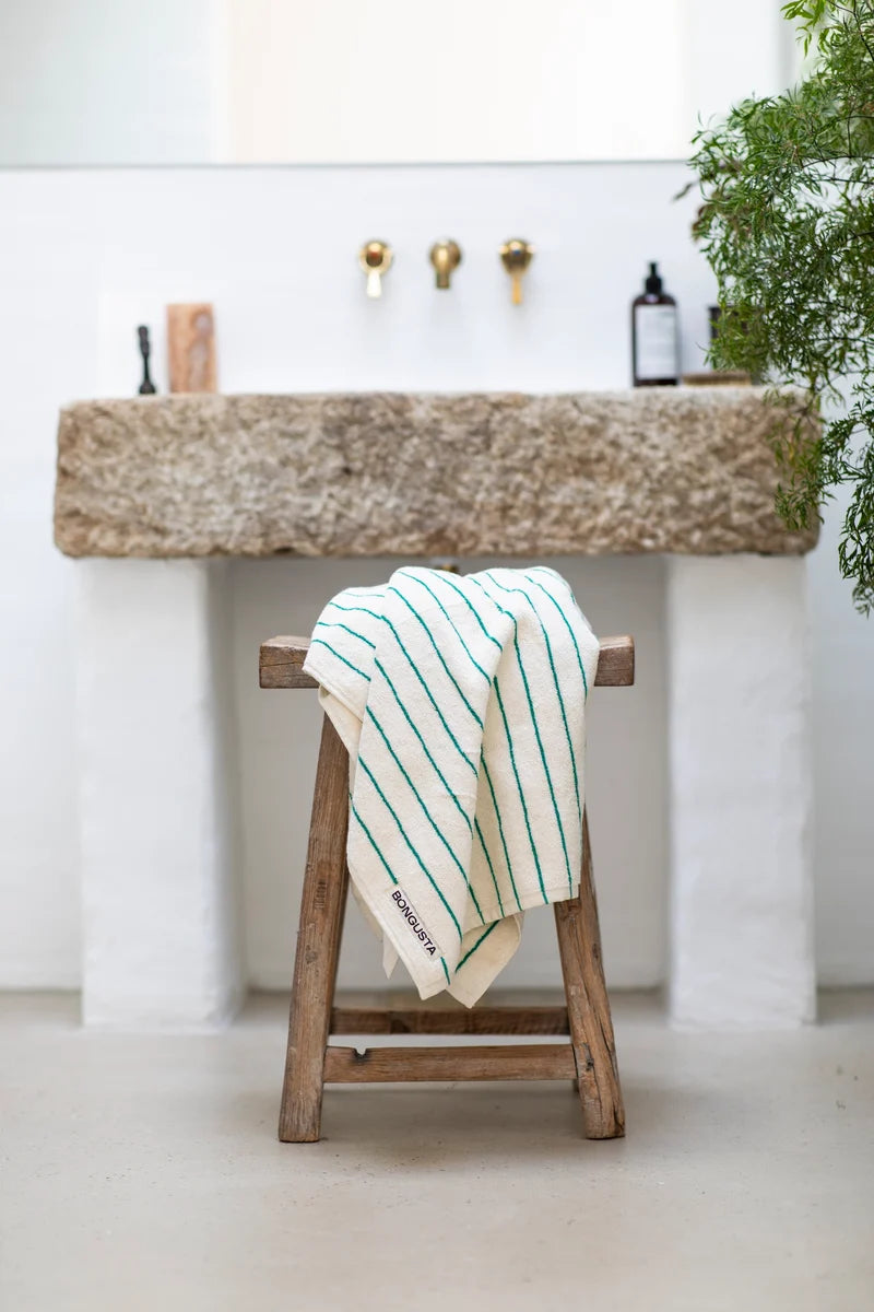 Bongusta Naram bathroom towel in pure white and grass green, displayed folded on a bathroom countertop with a modern setting.