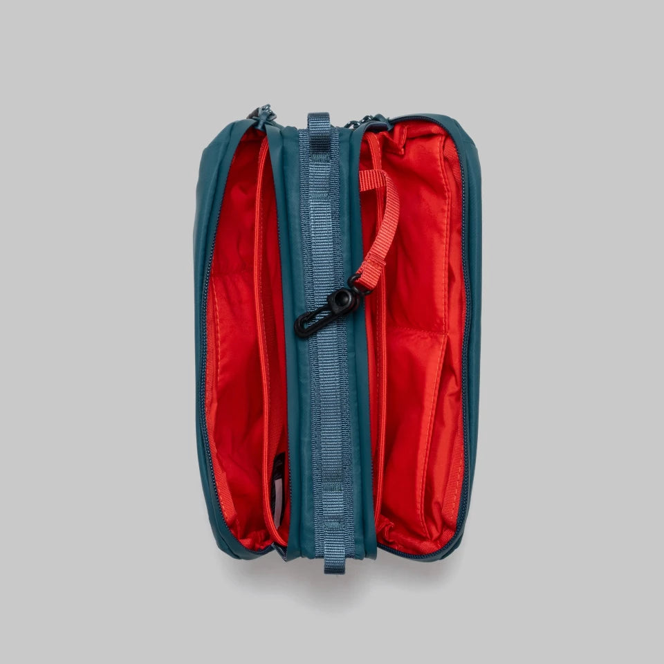Open teal bottle bag from topologie with red interior on a gray background
