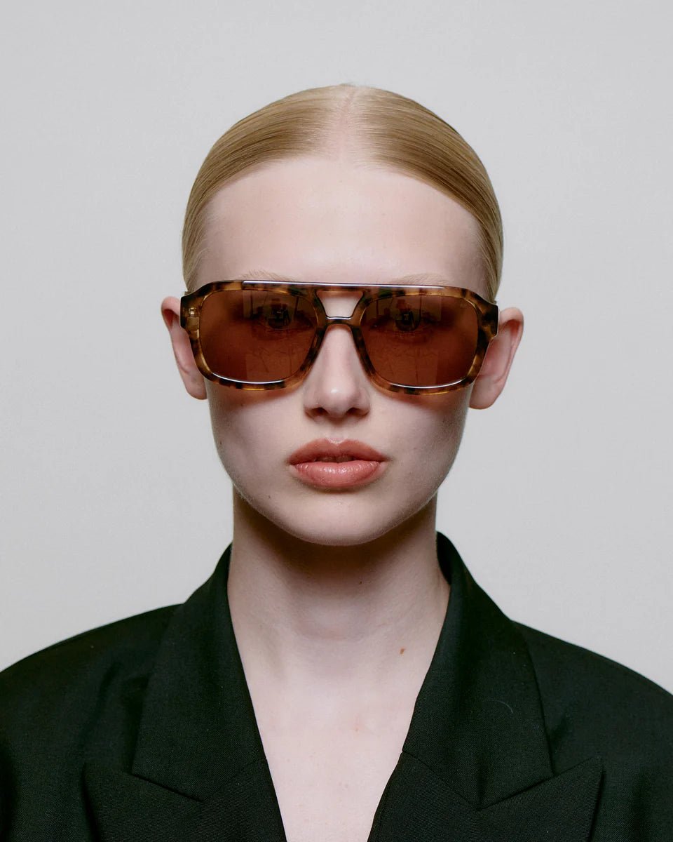 A. Kjaerbede Coquina Kaya sunglasses with round frames and tinted lenses, stylishly displayed on a neutral background.