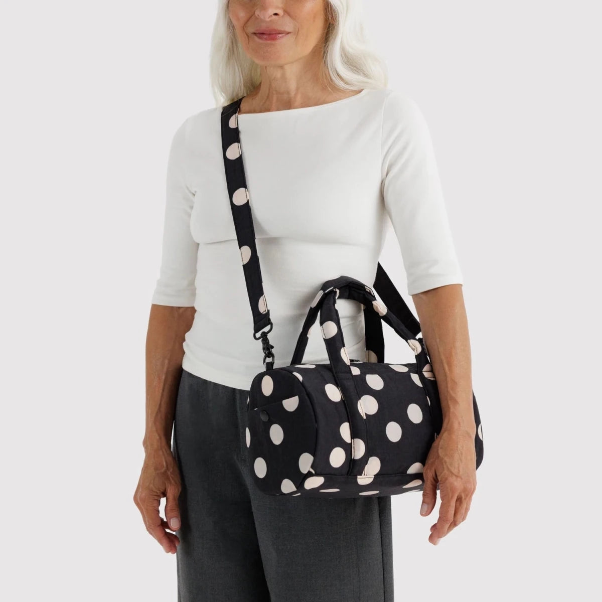 Black and cream polka dot nylon duffle bag by Baggu, showcasing its spacious design and sturdy handles.