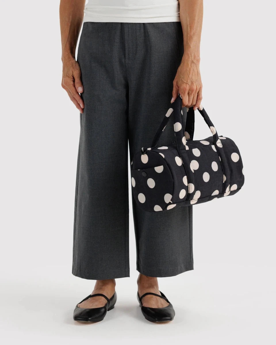Black and cream polka dot nylon duffle bag by Baggu, showing a spacious, lightweight travel bag with sturdy handles.