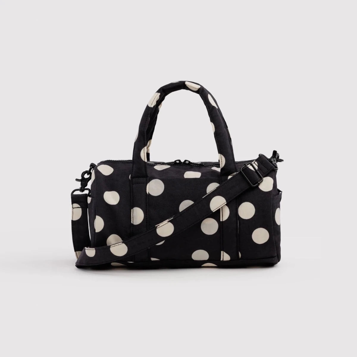 Black and cream polka dot nylon duffle bag by Baggu with sturdy handles and spacious interior for travel or gym use.