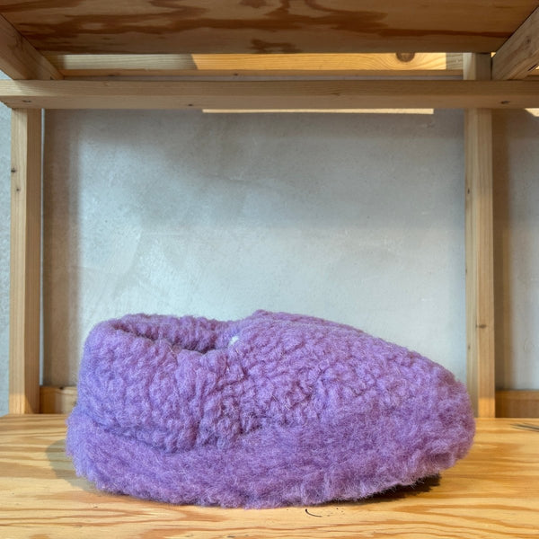 Purple textured object hanging on a wooden shelf