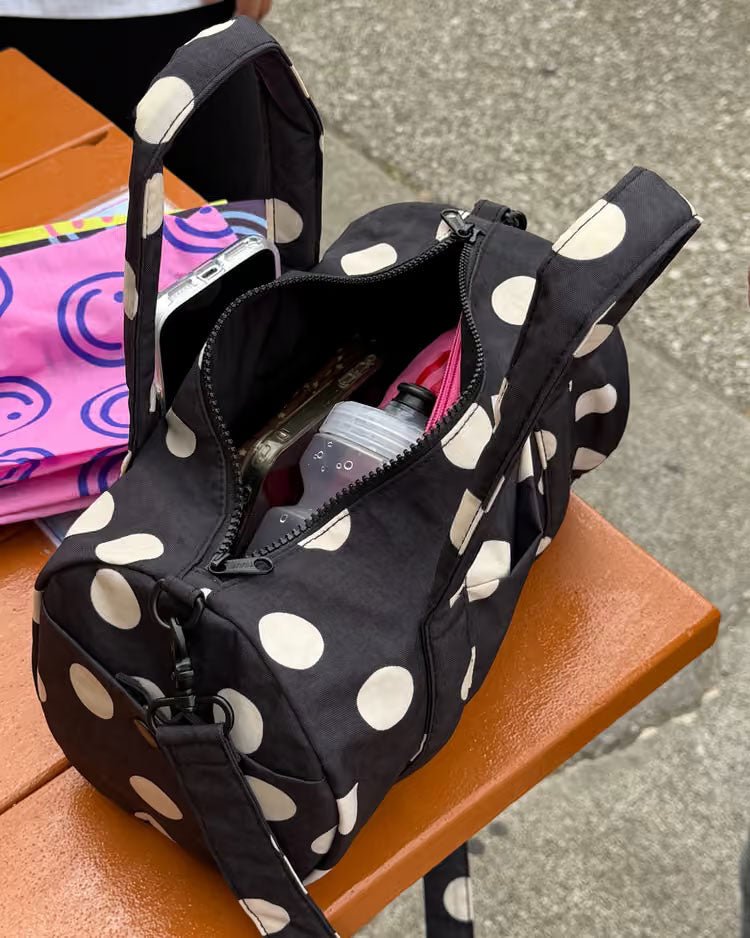 Black and cream polka dot nylon duffle bag by Baggu, showing a spacious, lightweight travel and gym bag with sturdy handles.