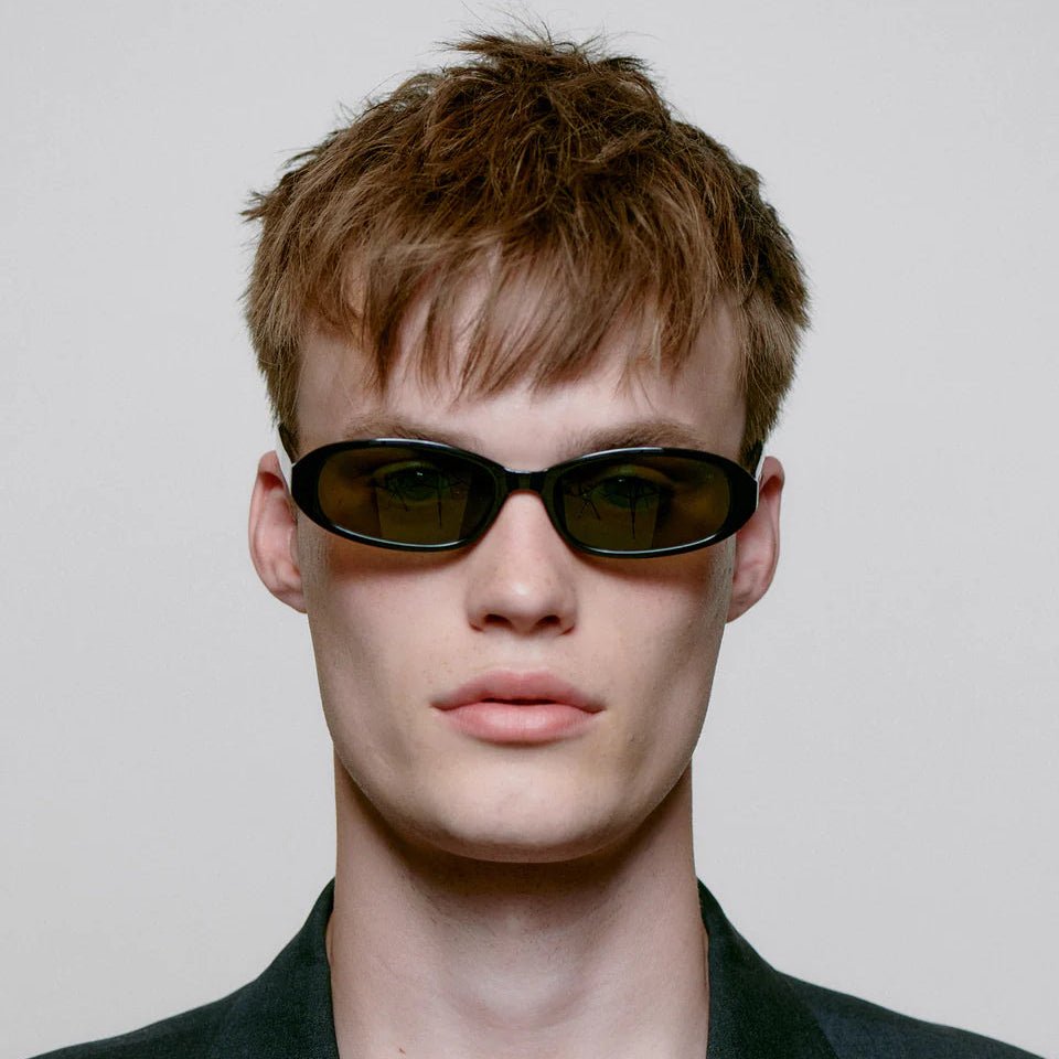A. Kjaerbede Macy sunglasses with stylish frame and dark tinted lenses, resting on a white background.
