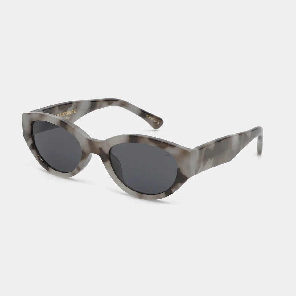 A. Kjaerbede Winnie sunglasses with round frames and dark lenses, stylishly worn on a person outdoors.