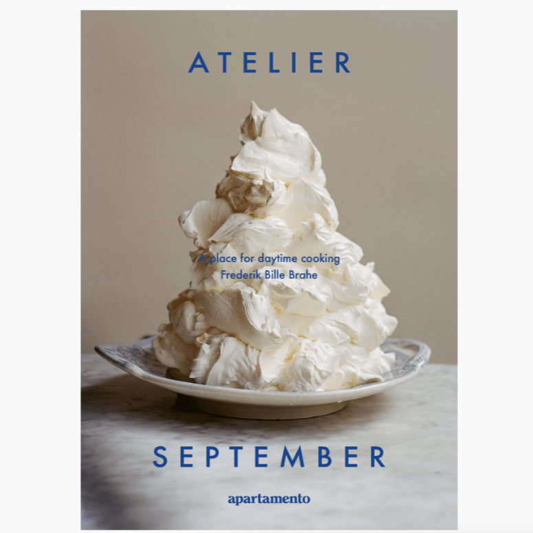 Open book titled "Atelier September: A Place For Daytime Cooking" by Apartamento, showcasing a cozy kitchen scene.