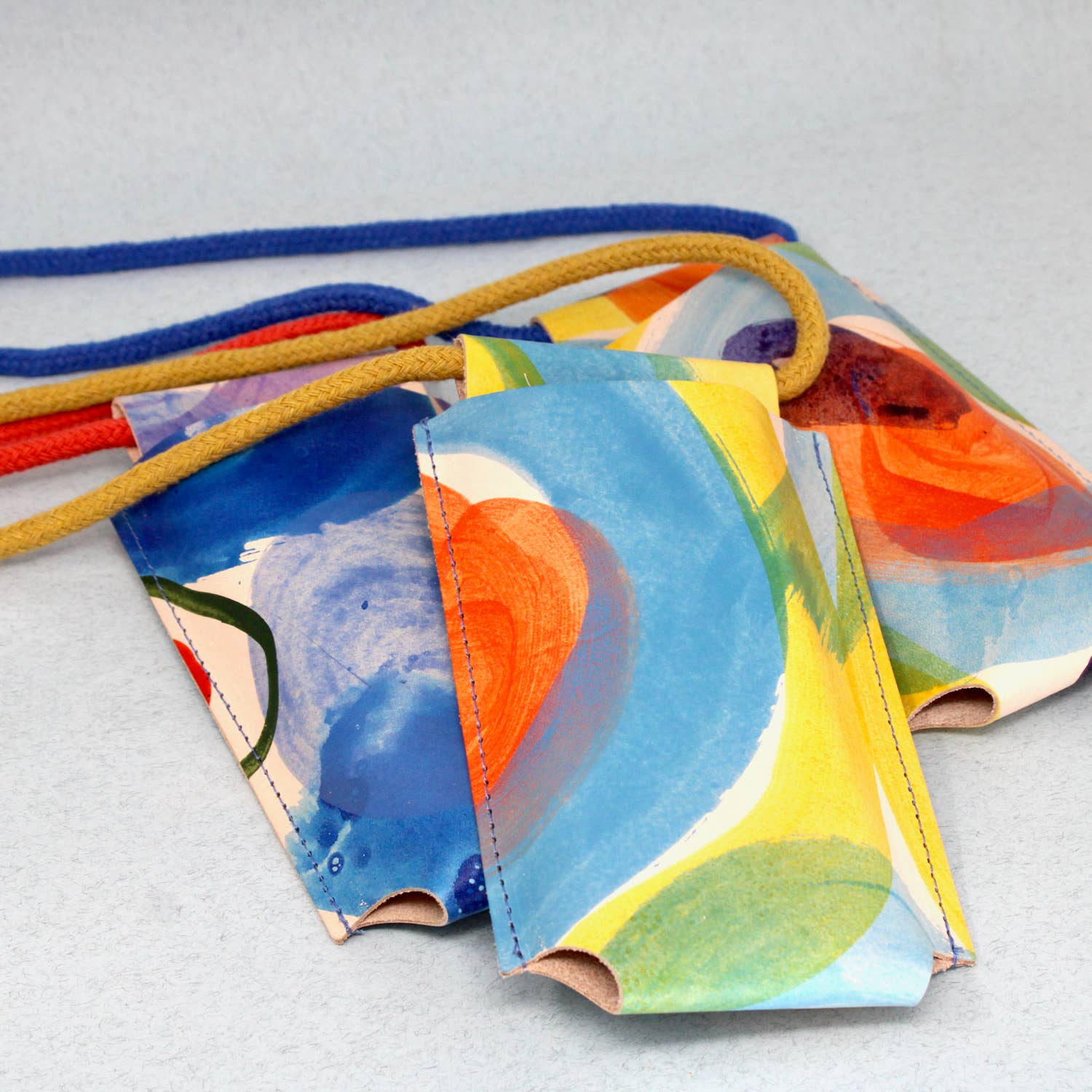 Hand-painted leather phone bag by Ark Colour Design, featuring vibrant, artistic designs on a stylish, compact leather accessory.