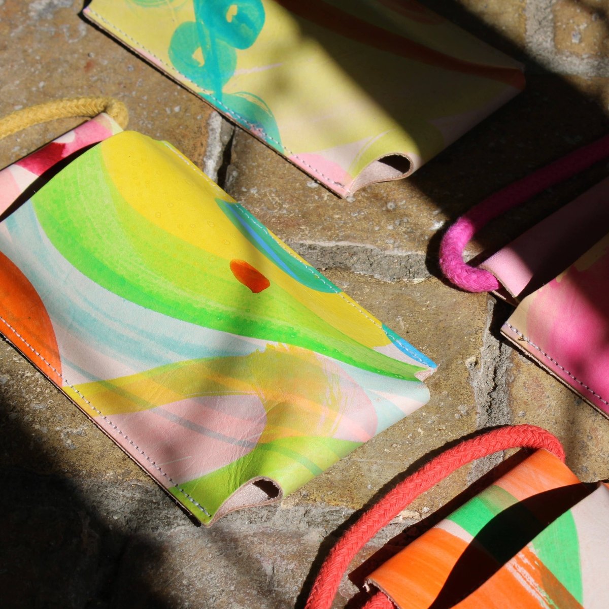 Hand-painted leather phone bag by Ark Colour Design featuring vibrant, artistic leather with a compact, stylish design.