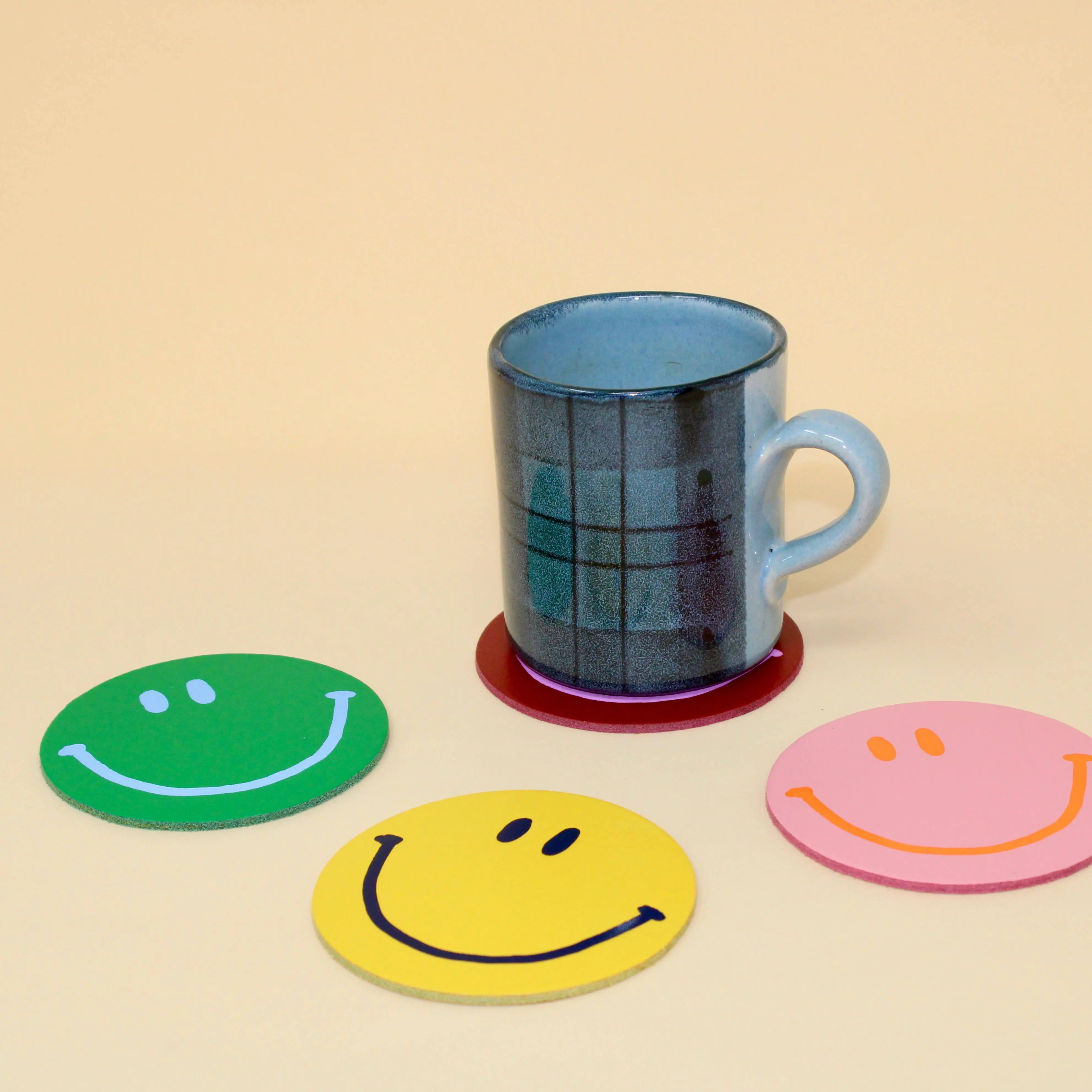 Set of four Happy Face Smilie leather coasters by Ark Colour Design, featuring cheerful smiley face designs on smooth leather surfaces.