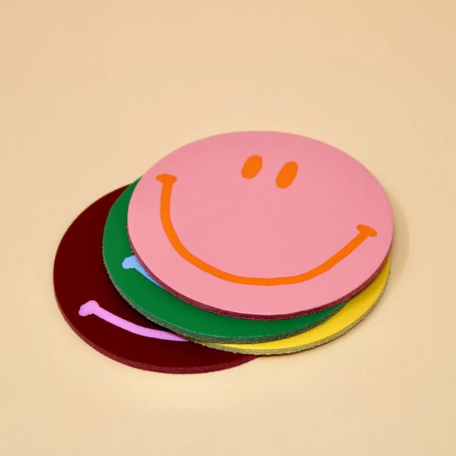 Set of four Happy Face Smilie leather coasters by Ark Colour Design, featuring cheerful yellow smiley face designs on leather.