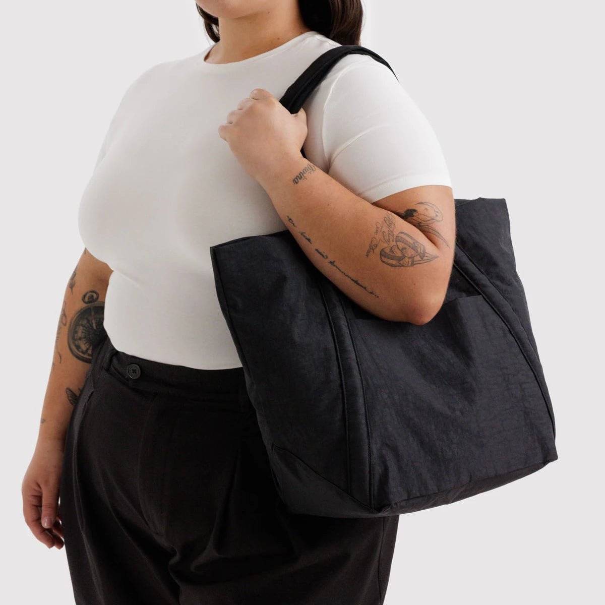 Person holding a black tote bag against a white background