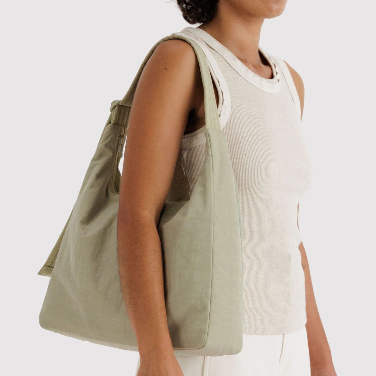 Person holding a green tote bag against a white background