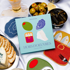 Hors d'oeuvres napkins with crackers, olives, and pickles on a white tablecloth.