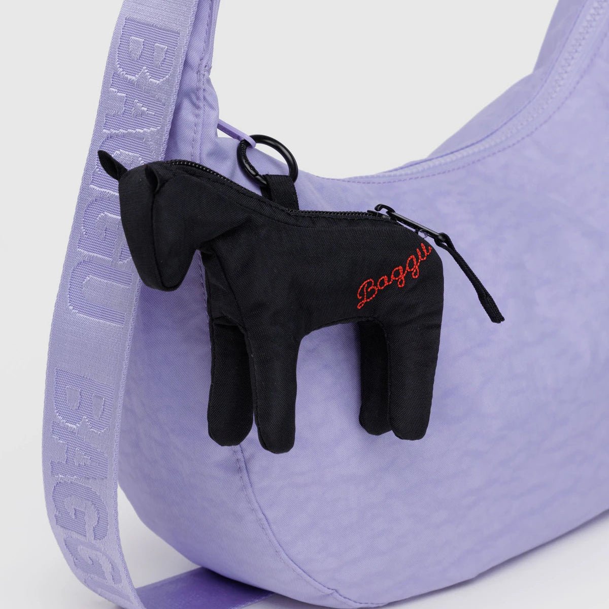 Purple bag with black horse-shaped charm attached on a white background