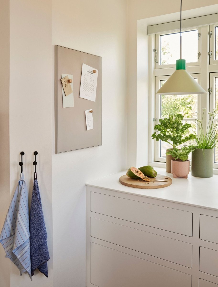 Green Hübsch Crayon pendant light hanging from the ceiling with a smooth, modern design.