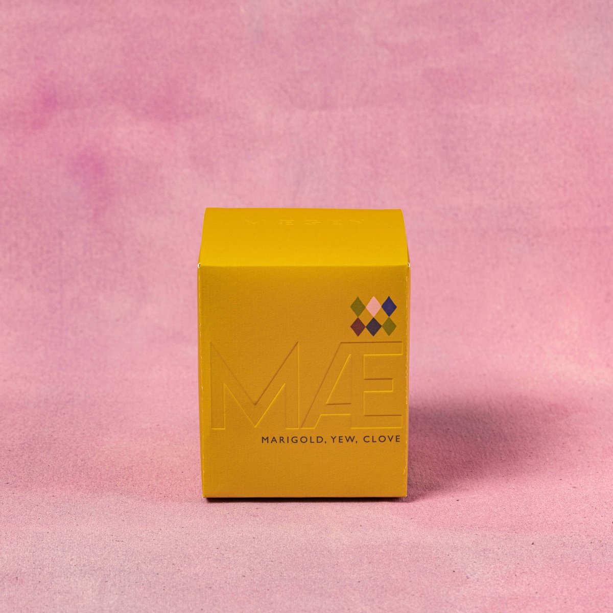 Yellow box with 'MAE' branding on a pink textured background