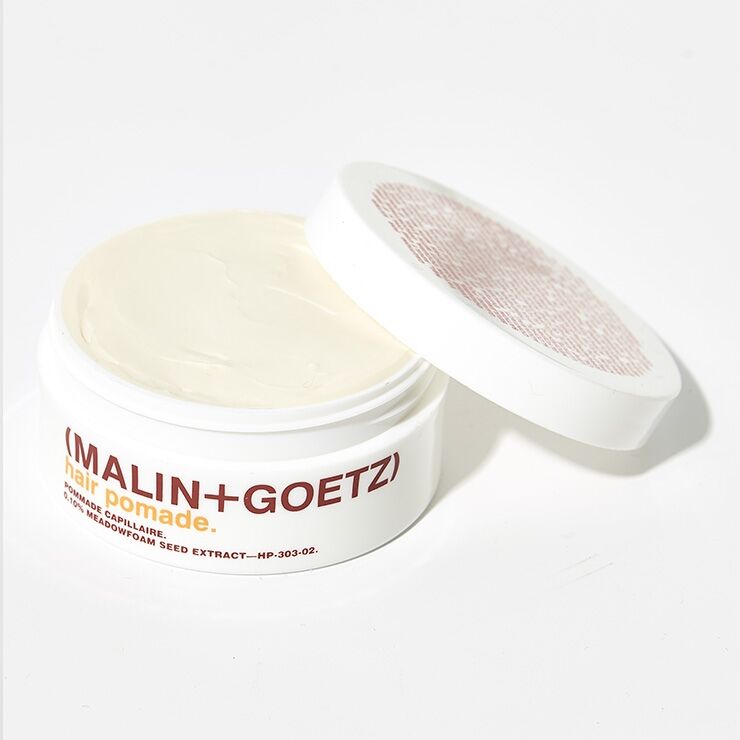 Malin+Goetz hair pomade in a jar, showing a smooth, shiny styling product for sleek hair control and shine.