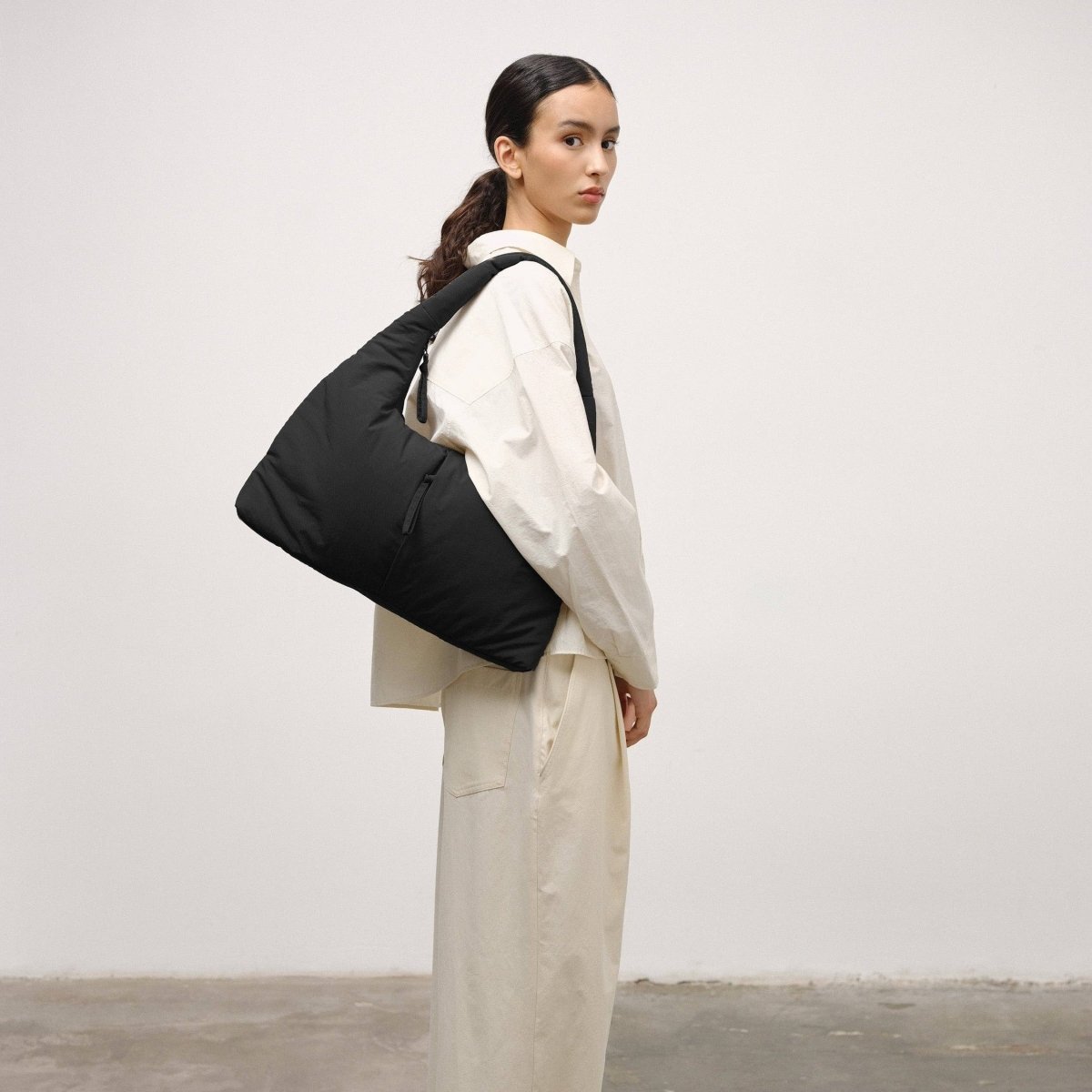Person wearing a black backpack in a minimalistic setting