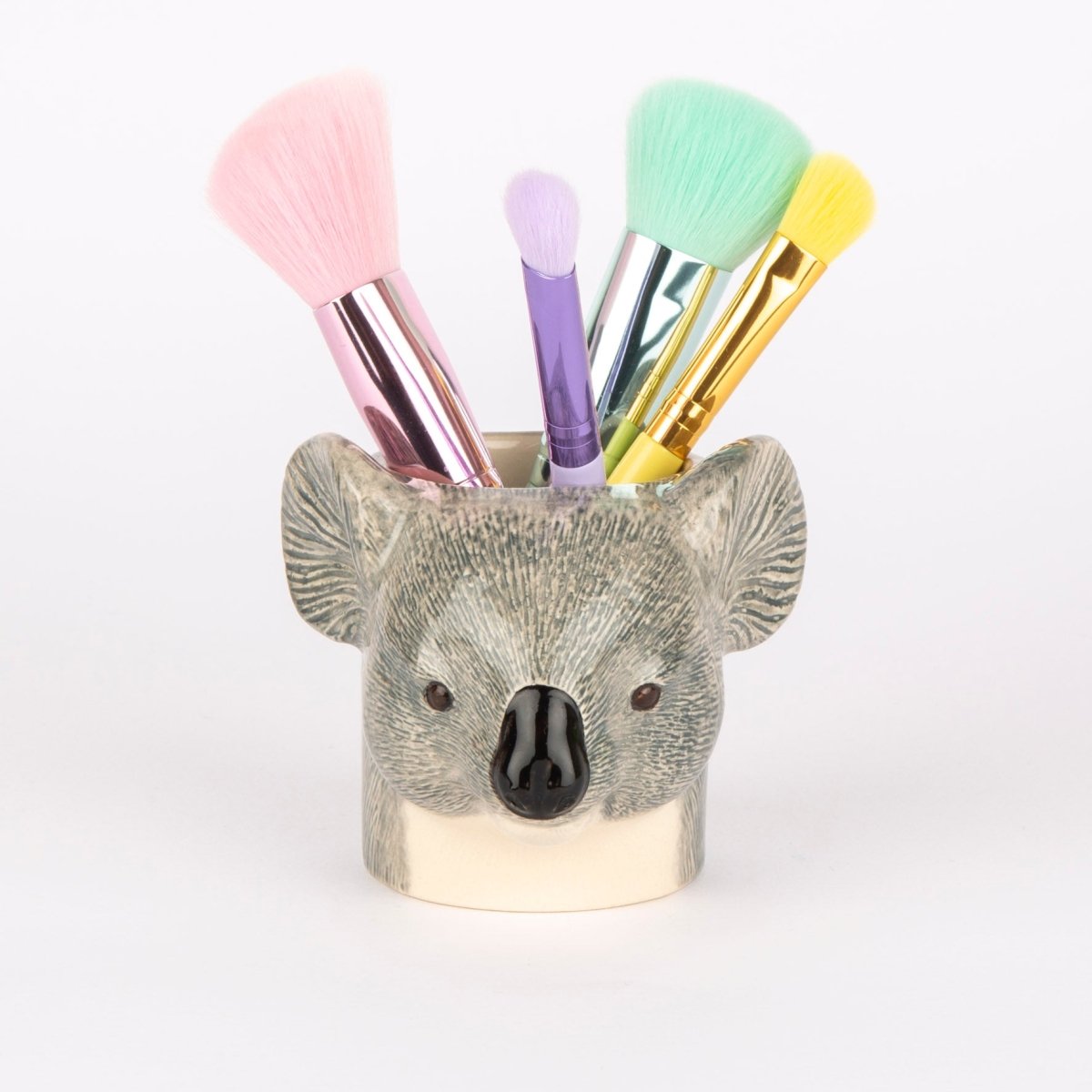 Koala-shaped makeup brush holder with colorful brushes on a white background