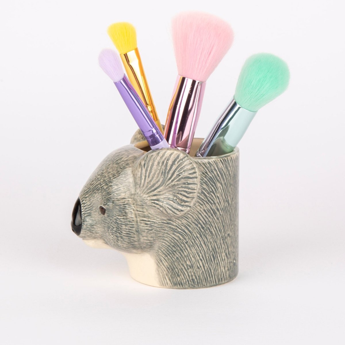 Makeup brushes in a koala-shaped holder on a white background