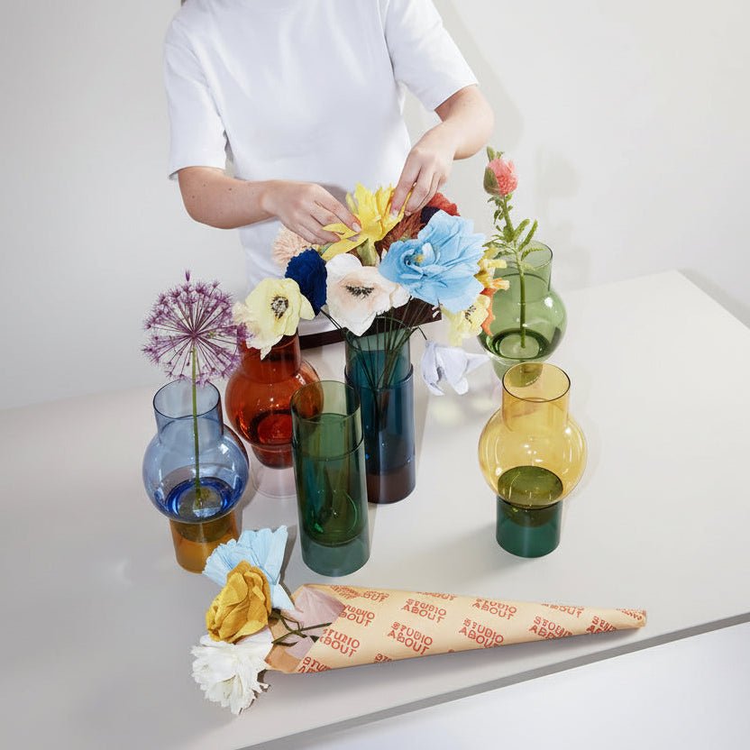 Set of colorful glass vases with flowers on a white background