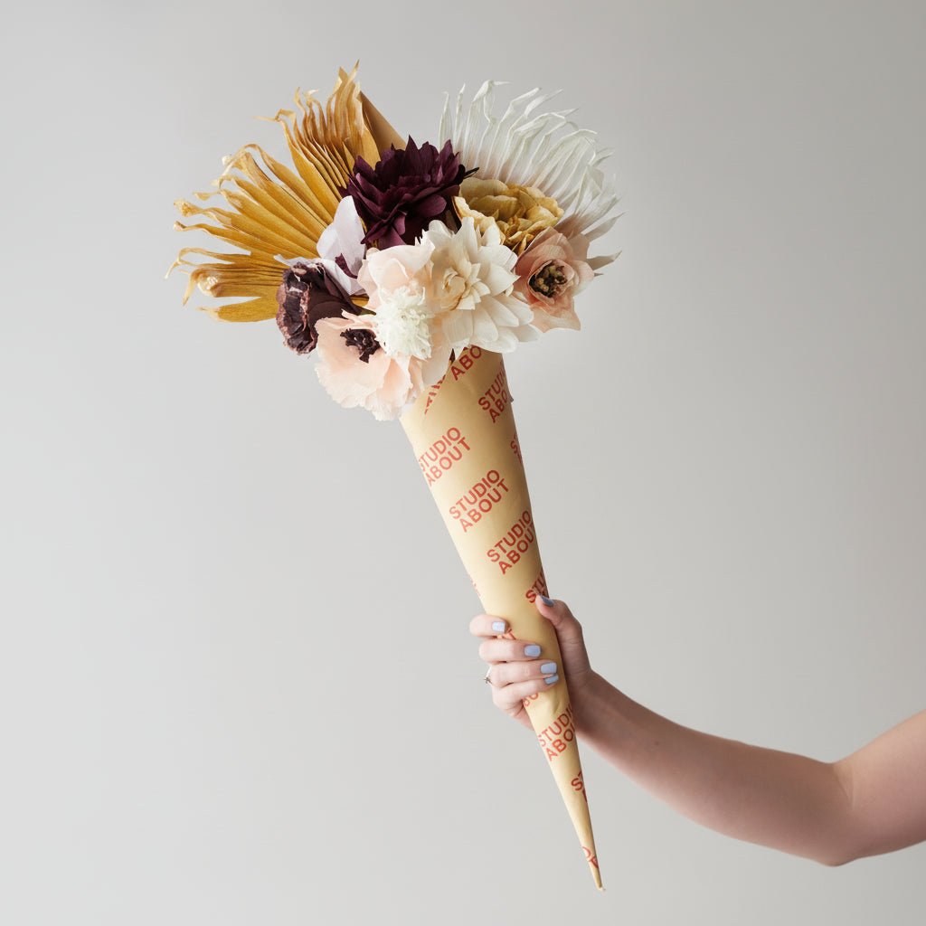 Floral arrangement in a paper cone with 'Studio About' branding against a plain background