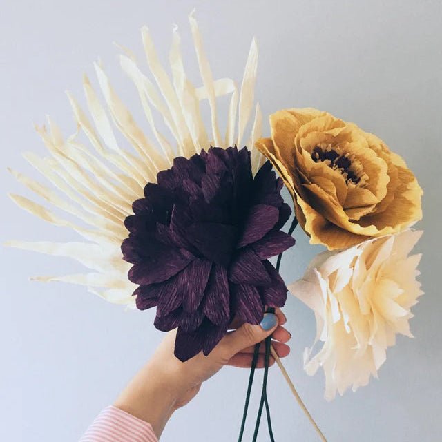 Hand holding a bouquet of flowers against a light gray background