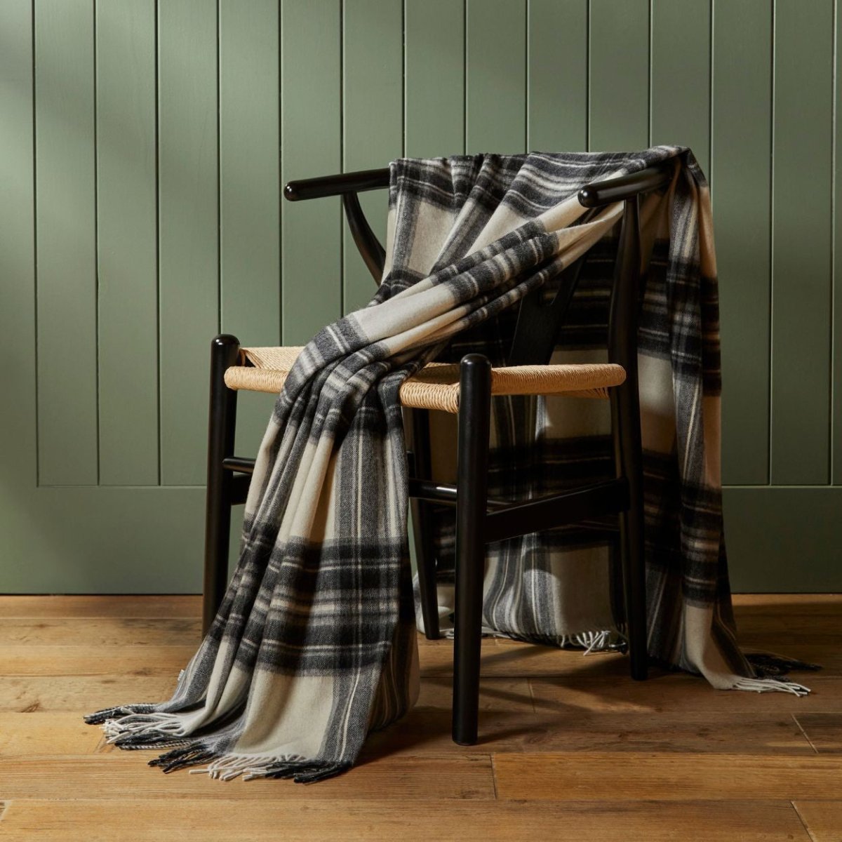 Soft Tweedmill lambswool wool blanket draped over a sofa, showcasing its cozy texture and natural wool color.