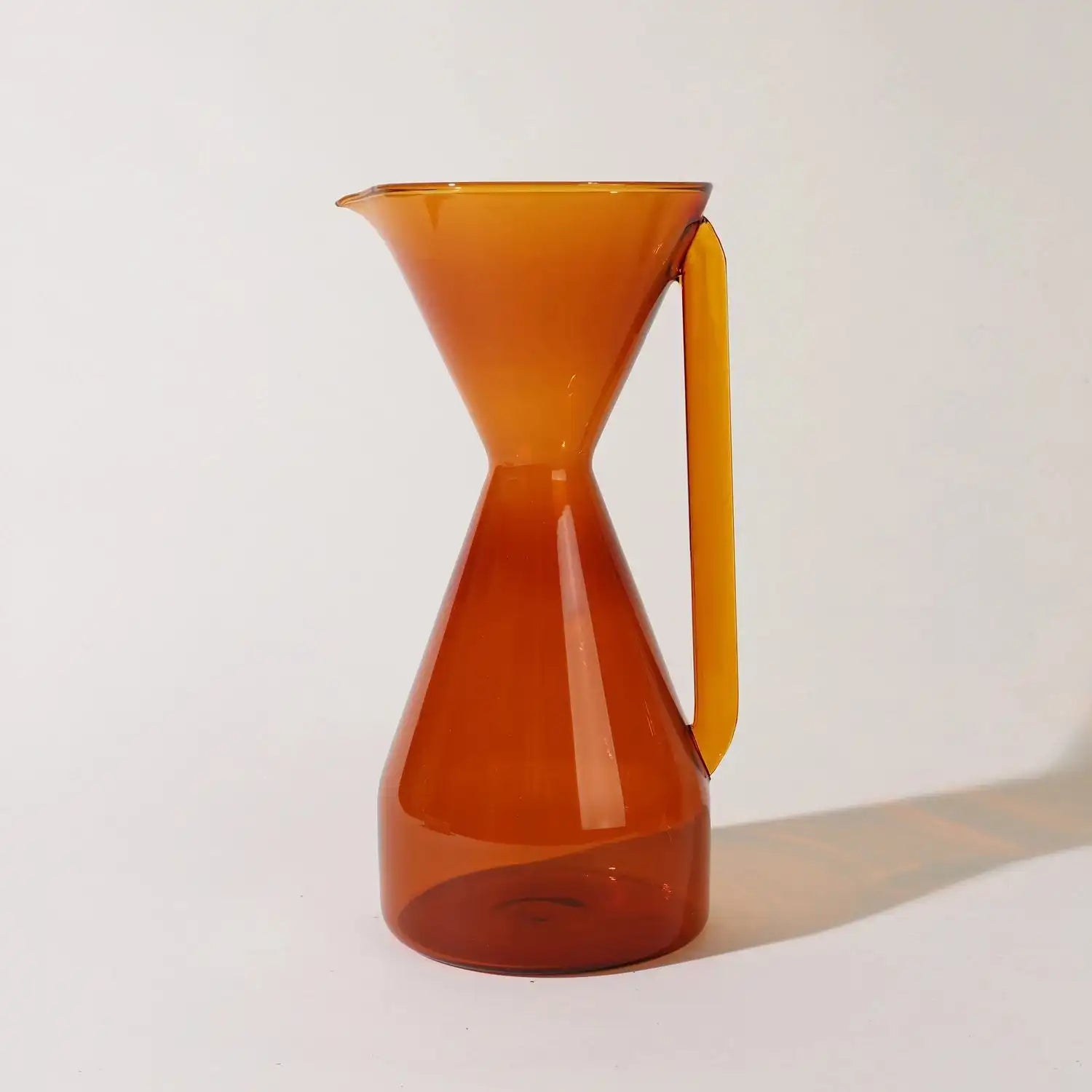 Yield coffee pour over carafe for brewing drip coffee, made of glass with a black handle and lid, on a wooden surface.