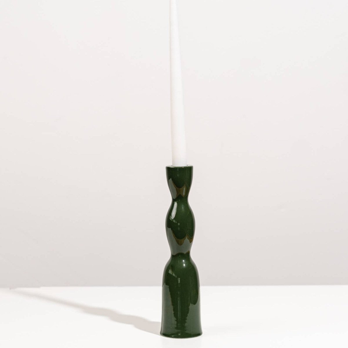 Tall dark green Wave Candleholder by YOD&CO with a sleek, curved design suitable for holding candles on a table or shelf.