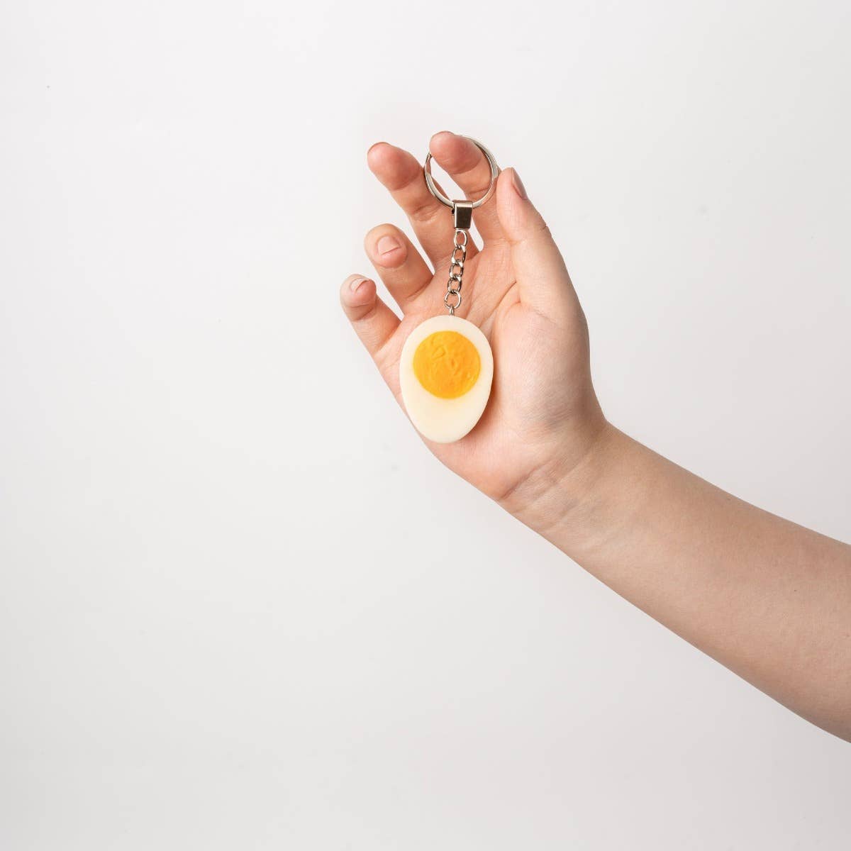 Yumazing hard-boiled egg keychain accessory with a realistic egg design, attached to a metal keyring, by Connectrade AG.